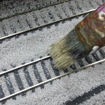 Coup de pinceau pour égaliser le ballast sur les traverses