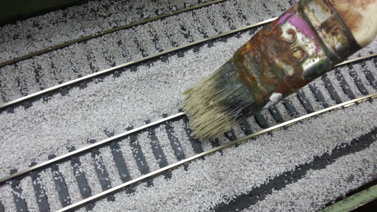 Coup de pinceau pour égaliser le ballast sur les traverses